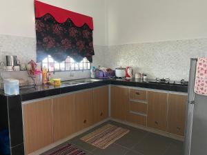 Kampong Ranggol PetaiにあるLadiya Homestay Islamicのキッチン(木製キャビネット、黒いカウンタートップ付)