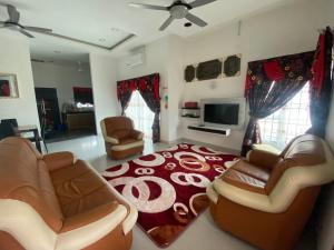 un soggiorno con divani e tappeto rosso di Ladiya Homestay Islamic 