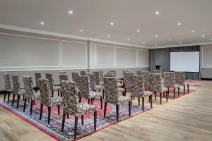 Zimmer mit einer Reihe von Stühlen und einem Bildschirm in der Unterkunft Premier Hotel Cape Town in Kapstadt