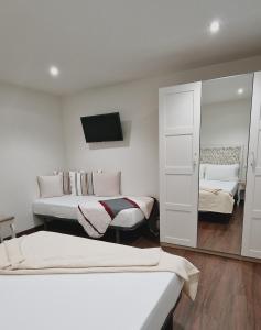 塔皮亞德卡薩列戈的住宿－Hotel El Panorama，白色的客房配有两张床和镜子