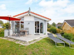 a white cottage with a table and chairs and an umbrella at 4 person holiday home in GROEMITZ in Grömitz