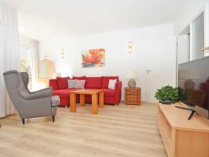 a living room with a red couch and a tv at Villa am Park - Apt. 02 Düne in Ostseebad Sellin