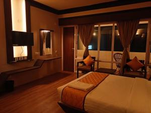 a hotel room with a bed and a television at Golden Peaks Hotel & Restaurant in Kalimpong
