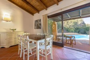 jadalnia ze stołem i krzesłami oraz basenem w obiekcie Villa Dalia w mieście Stintino