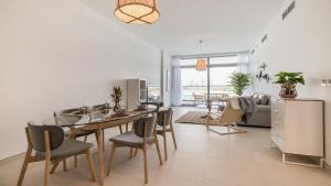uma sala de estar com uma mesa e cadeiras e um sofá em Hashtag Holiday Home - Luxury 2BDR Apartment on The Palm Azure Residences em Dubai