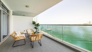 uma varanda com cadeiras e vista para a água em Hashtag Holiday Home - Luxury 2BDR Apartment on The Palm Azure Residences em Dubai