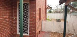 a brick house with a white fence and a door at Kennington Units Family in Kennington