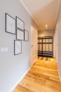 a hallway with wood floors and framed pictures on a wall at Komfortowy apartament z parkingiem in Wrocław
