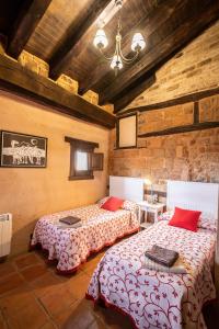a bedroom with two beds in a room with brick walls at Sierra de Gata EL CORRAL DE LA HIGUERA in Torre de Don Miguel