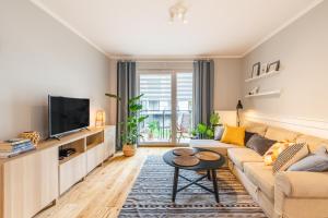 een woonkamer met een bank en een tv bij Komfortowy apartament z parkingiem in Wrocław