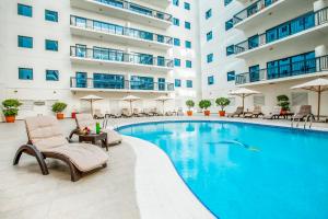 a swimming pool in a hotel with chairs and a building at Golden Sands Suites in Dubai