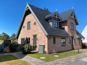 uma casa de tijolos castanhos com um telhado preto em Ferienhaus Inselwind Sylt em Westerland