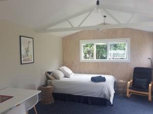 a bedroom with a bed and a desk and a window at Beach Break Cabin - short walk to beach and cafes in Waihi Beach