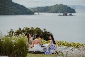 Amatara Welleisure Resort في شاطئ بنوا: ثلاث نساء يجلسن حول طاولة بجانب البحيرة