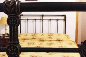 a bed with a black frame with a floral bedspread at Tía Clotilde es una casa grande ideal para familias y grupos de amigos in Cabezas Bajas