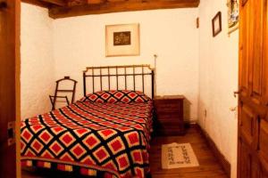 a bedroom with a bed with a red and black blanket at Casa Tía Modesta es una cálida y acogedora casa rural. in Cabezas Bajas