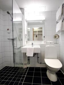 a white bathroom with a sink and a toilet at Hotell Högland in Nässjö