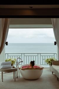 Amatara Welleisure Resort في شاطئ بنوا: امرأة في حوض استحمام في غرفة مع نافذة