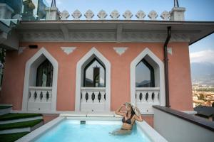 uma mulher numa piscina ao lado de um edifício em La Portineria Luxury B&B em Piancogno