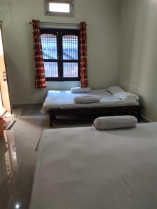 Habitación con 3 camas y ventana en Sunrise Lodge en Varanasi