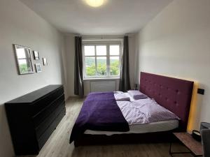 1 dormitorio con cama morada y ventana en Large 3 bedroom apartment with city skyline view, en Karlovy Vary