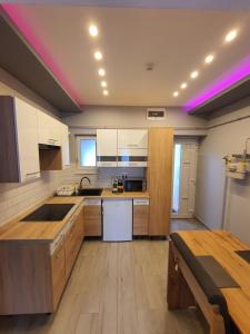 a kitchen with wooden cabinets and a purple light on the ceiling at Belvárosi Exkluzív Loft in Debrecen
