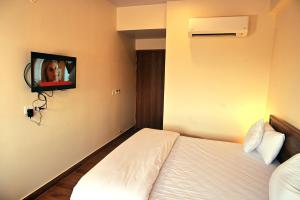 um quarto de hotel com uma cama e uma televisão na parede em The Sarai, Hotel em Jaipur