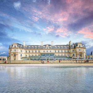 - un grand bâtiment à côté d'une étendue d'eau dans l'établissement Grand Hôtel Des Thermes, à Saint-Malo