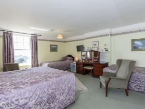 1 dormitorio con cama, escritorio y silla en Bucklawren Farm, en Looe