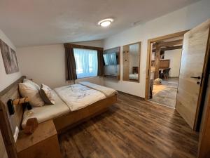 a bedroom with a bed in a room with wooden floors at Inn-Apartments in Prutz