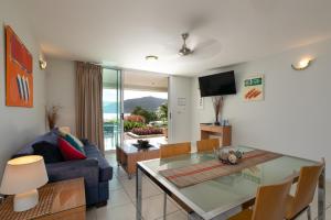 a living room with a blue couch and a glass table at Waterview Airlie Beach in Airlie Beach