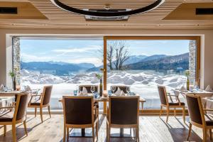a dining room with a view of snow covered mountains at Tratterhof Mountain Sky Hotel in Maranza