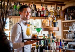 ein Barkeeper mit einem Tablett mit zwei Cocktails darauf. in der Unterkunft Tratterhof Mountain Sky Hotel in Meransen