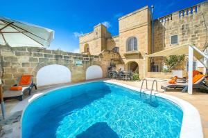 una grande piscina di fronte a un edificio in pietra di Gawhra Holiday Home a Xagħra