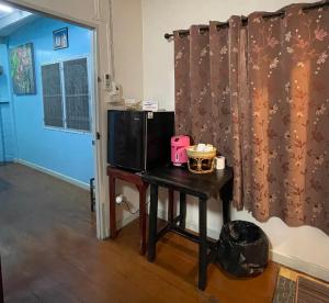 a room with a table with a microwave and a television at Hidden Lumpu in Bangkok