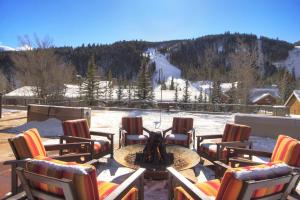 a patio with chairs and a fire pit in the snow at Slopeside in Keystone