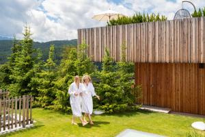 duas mulheres de branco a andar num quintal em Tratterhof Mountain Sky Hotel em Maranza