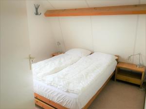 a bedroom with a bed with white sheets at Vakantiehuis Domburg 100 meter van het strand - veel privacy - eigen parkeerplaats. in Domburg