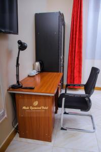 a desk with a chair in front of a television at Mbale Rosewood Hotel in Mbale