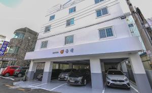 een wit gebouw met auto's ervoor geparkeerd bij Geoje Dongbeck Hotel Gohyeon in Geoje 