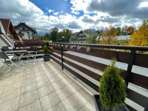 a balcony with a wooden fence and a table and trees at Kamieniec No5 Apartments in Zakopane