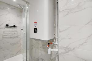 a shower in a bathroom with white marble at CMG - Cosy studio Le Marais in Paris