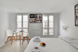 a white room with a bed and a table and chairs at CMG - Cosy studio Le Marais in Paris