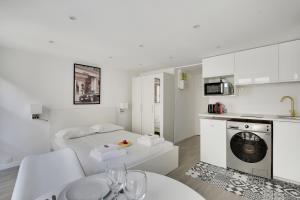 a white apartment with a bed and a kitchen at CMG - Cosy studio Le Marais in Paris