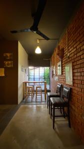 a room with chairs and tables and a brick wall at Batu Bata Guesthouse in Kuching