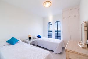 two beds in a white room with a clock on the wall at Aldea Beach 39 - Fantástica casa a pie de playa in Manilva