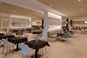a dining room with tables and chairs and a restaurant at HG Jardín de Menorca in Son Bou