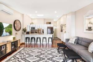 a living room with a couch and a kitchen at Cute as a Button - Picket Fence 3 Bed Stylish Home in Unley
