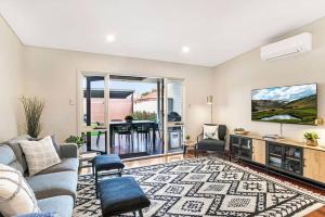 a living room with a couch and a tv at Cute as a Button - Picket Fence 3 Bed Stylish Home in Unley