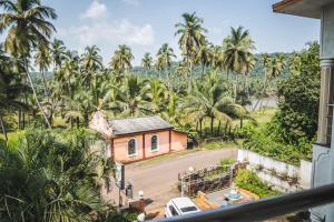 Corgao的住宿－Dhanashree Riverview Hotel，棕榈树房屋的阳台享有风景。